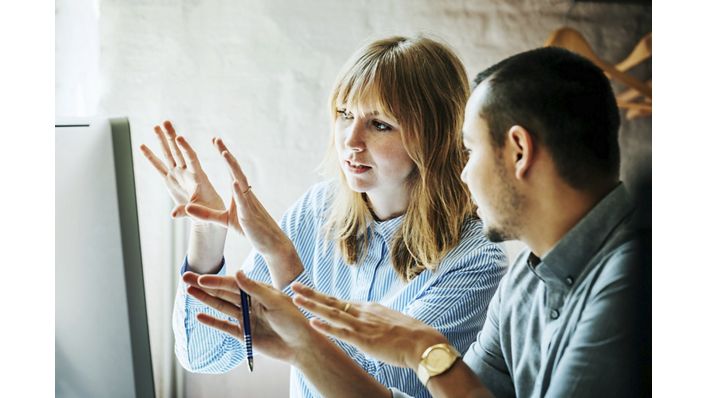 Two startup business colleagues problem-solving at a computer together in the office.